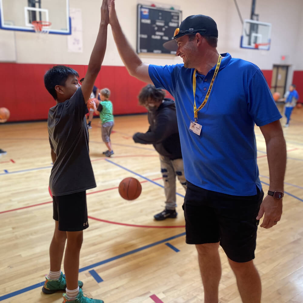 basketball-coach-kid coach giving a high five to a pre-teen in a gym