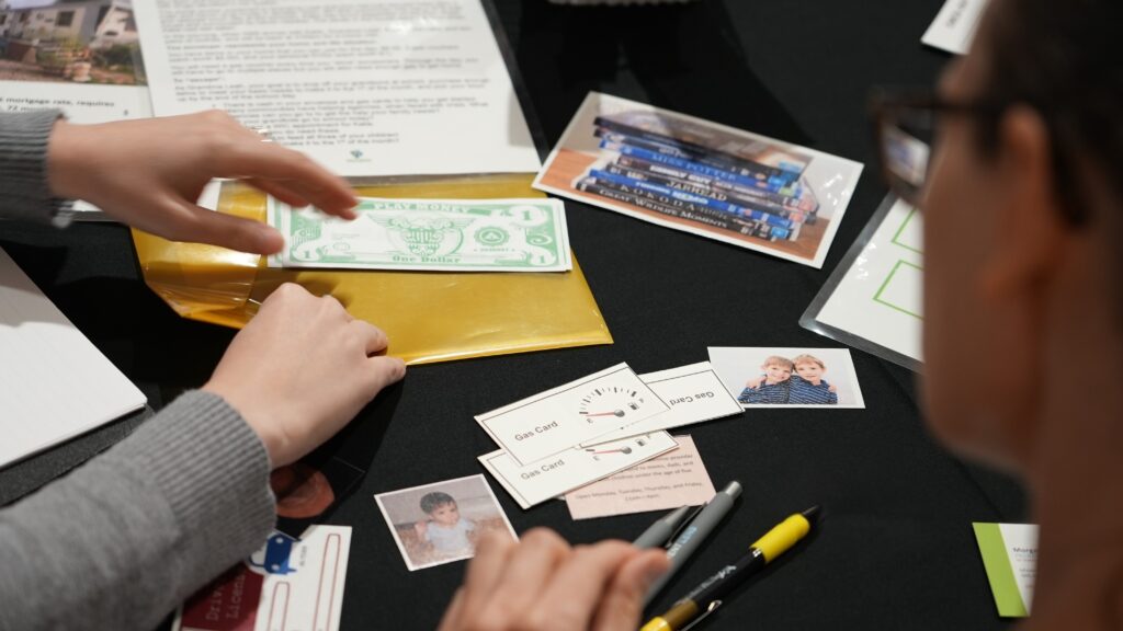 Poverty Escape Room participants are showing working through case materials as a team.