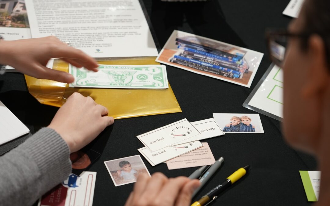 Poverty Escape Room participants are showing working through case materials as a team.